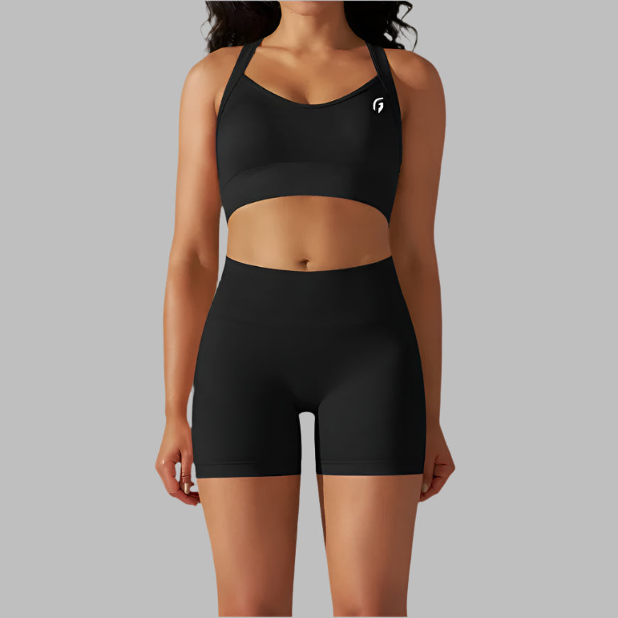 A woman wearing a Black sports bra and shorts set on a grey background